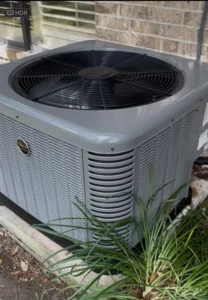 Outdoor heat pump condenser unit positioned beside a home.