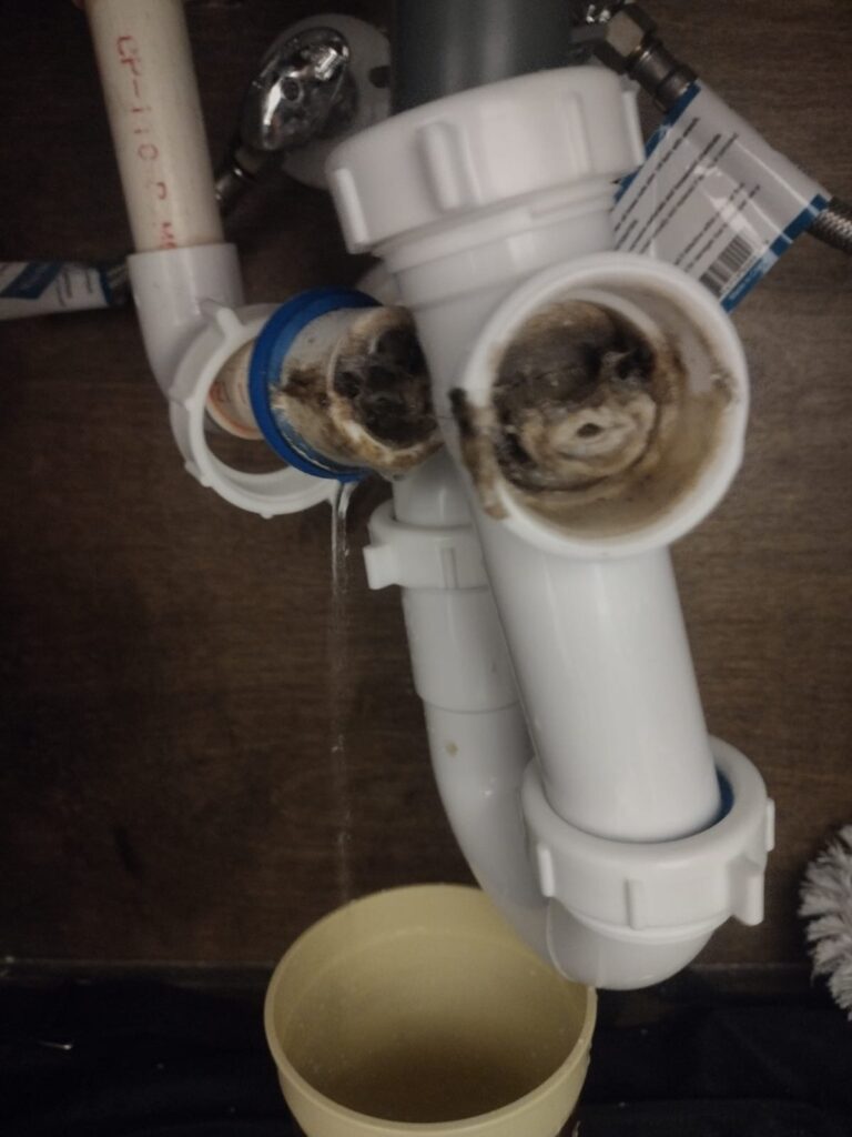 Damaged AC condensate drain assembly leaking water during HVAC repair in Edinburg, Texas