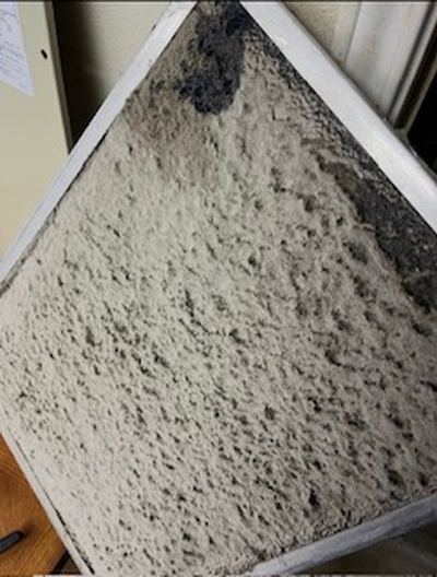 Dirty HVAC air filter clogged with dust and debris, restricting airflow and reducing air conditioner efficiency.